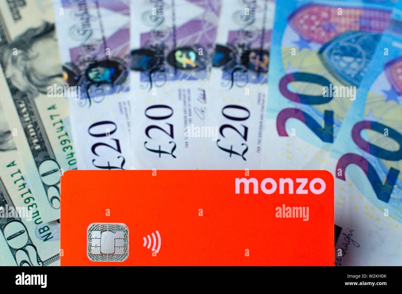 Monzo bank card on the cash of different countries. Card with no fee for money exchange is perfect for travel. Stock Photo