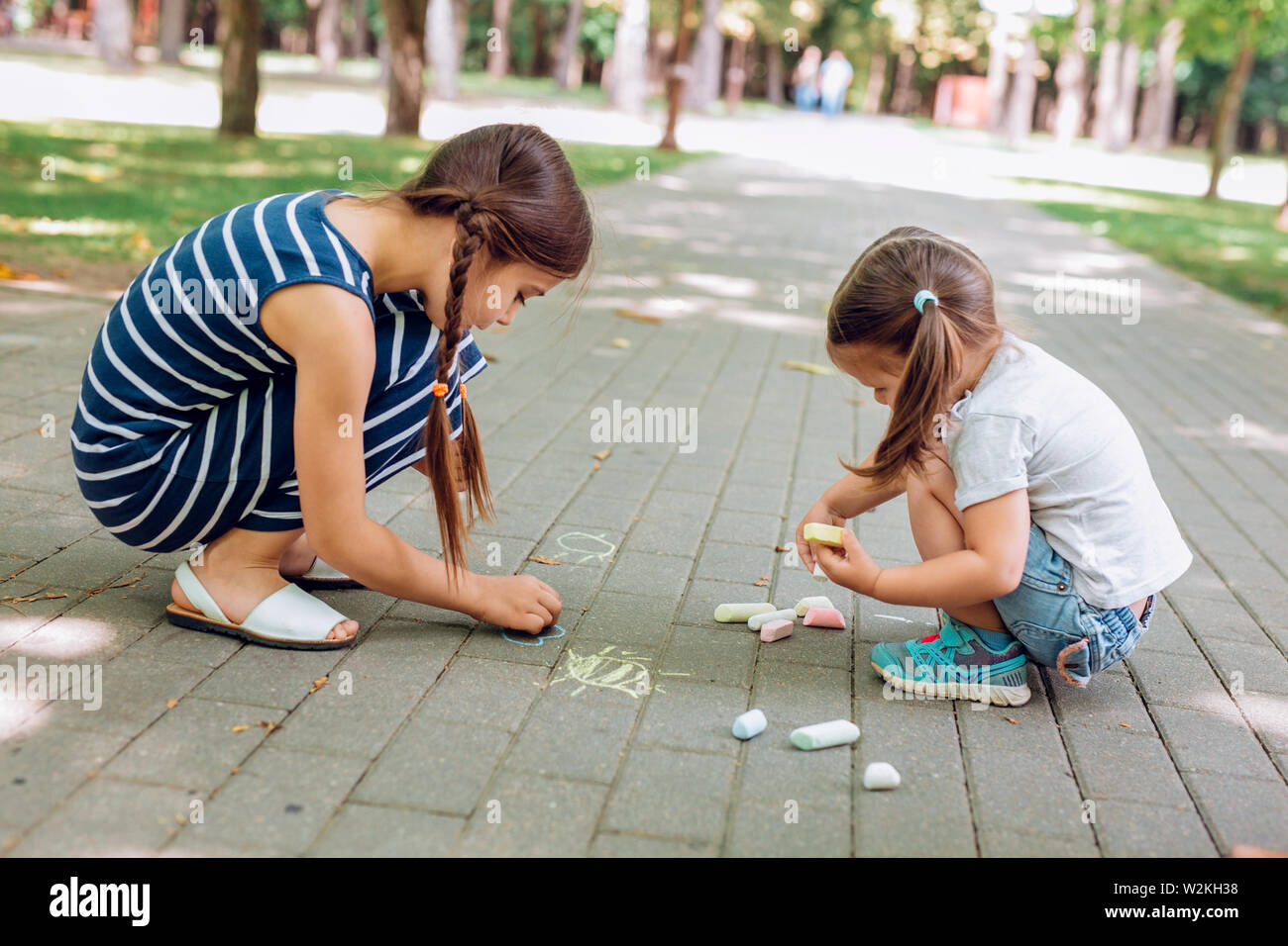 Two Cute Little Girls Sitting And Drawing With Chalk On Asphalt In Park In Summer Day Stock Photo Alamy Two Cute Little Girls Sitting And Drawing With Chalk On Asphalt In Park In Summer Day Stock Photo Alamy