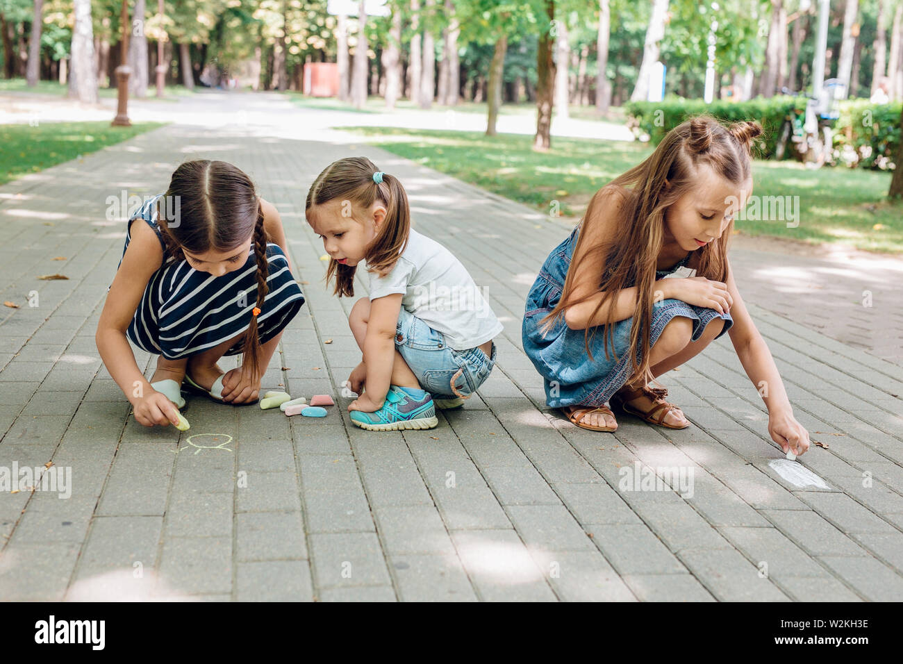Three Cute Little Girls Sitting And Drawing With Chalk On Asphalt In Park In Summer Day Stock Photo Alamy Three Cute Little Girls Sitting And Drawing With Chalk On Asphalt In Park In Summer Day Stock Photo Alamy
