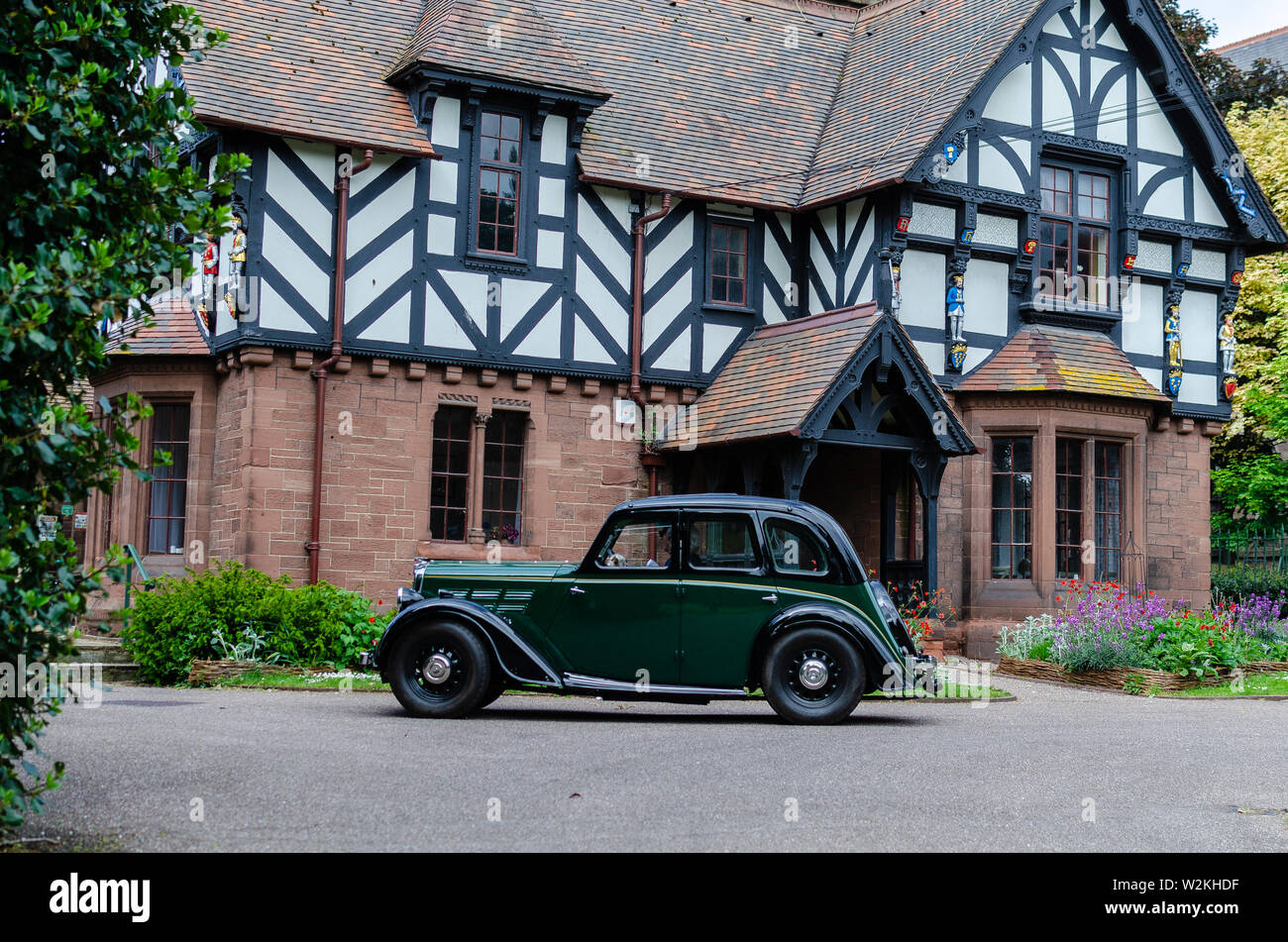 Elegant dark green retro car in front of old tudor house. Classic cars festival 'Brums and Buns' at Chester, UK. Stock Photo