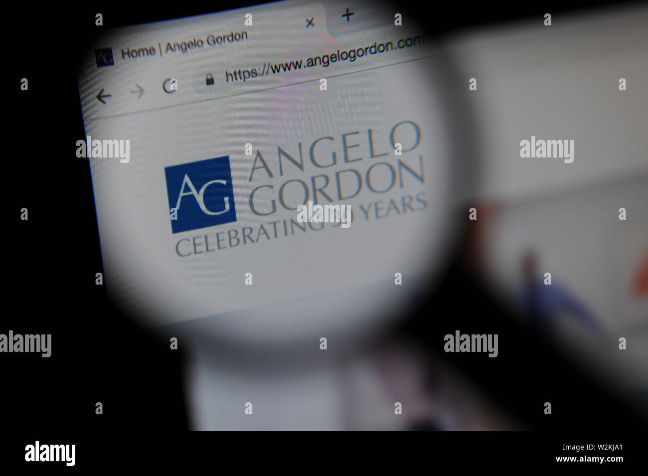 The Angelo Gordon financial website seen through a magnifying glass Stock Photo