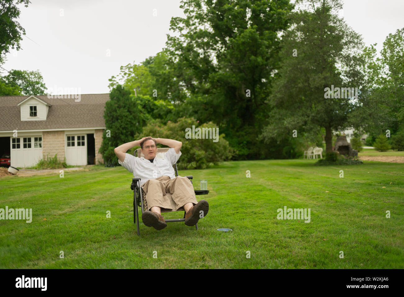 a middle aged caucasian man reclines in his backyard in suburban Philadelphia, suburbs Stock Photo