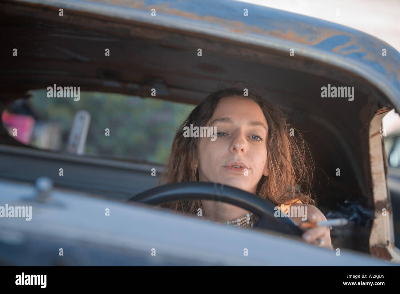 an attrrative young white woman in a car with a cigarette Stock Photo