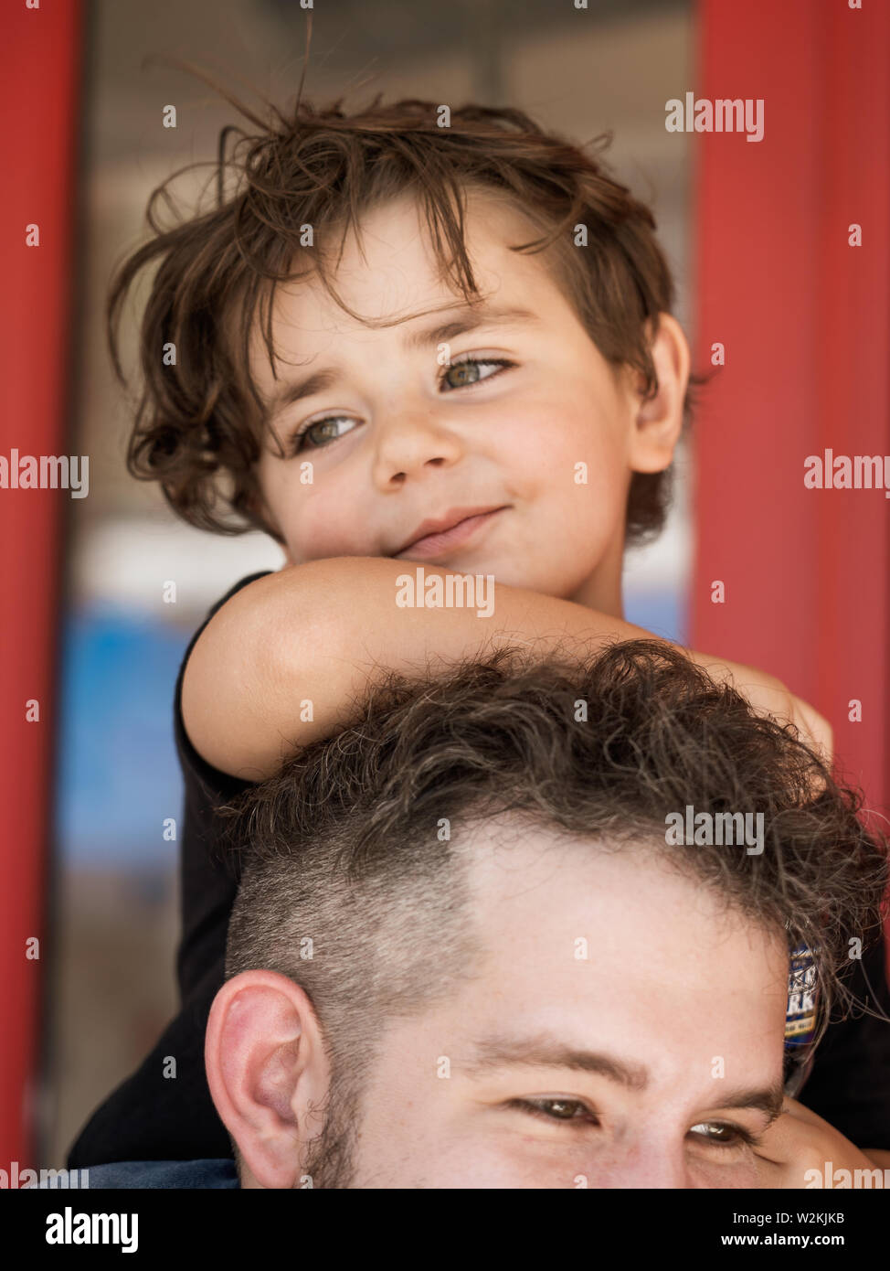 a young child sits on the shoulders of an adult  on south street in south Philadelphia Stock Photo