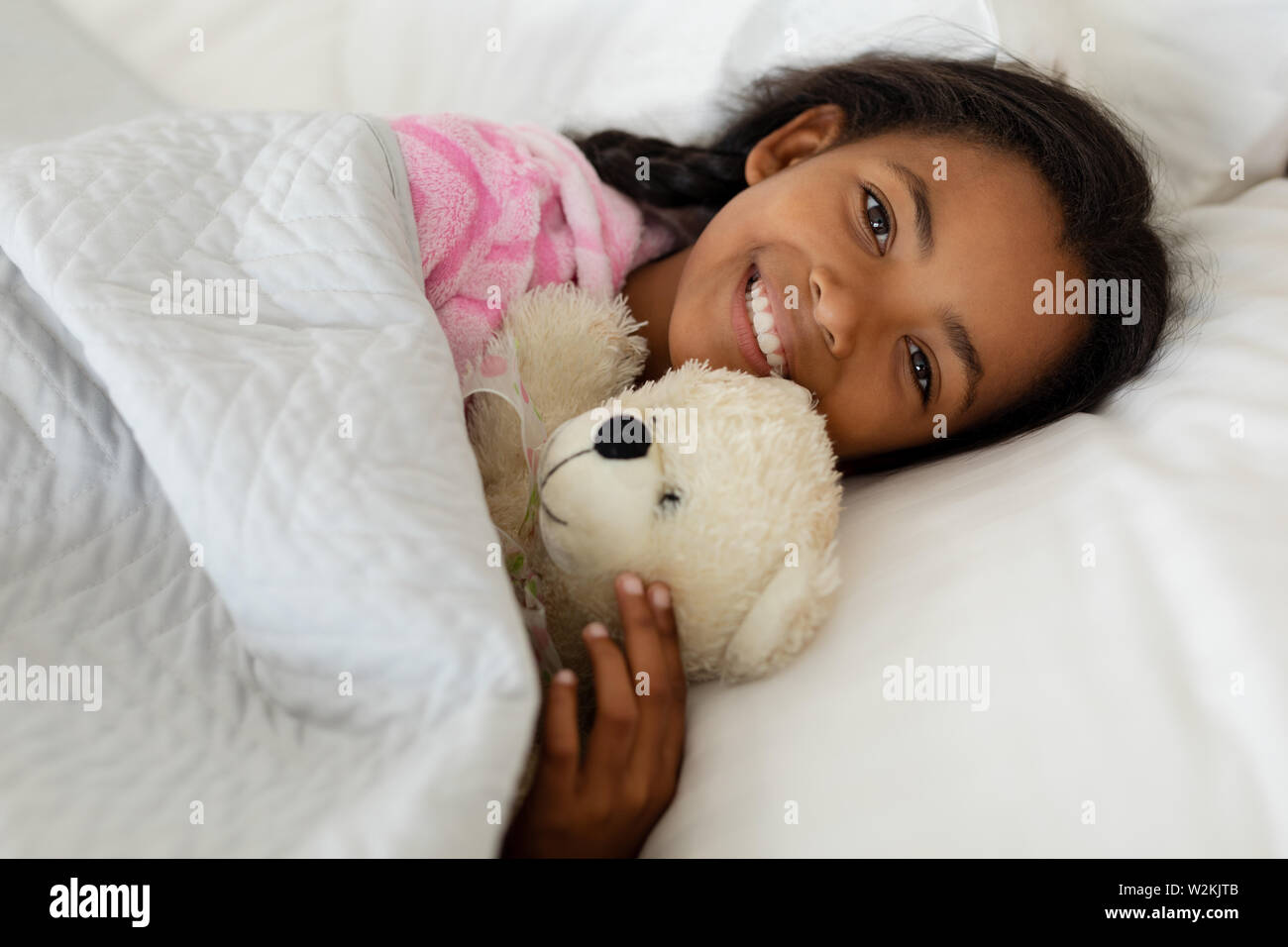 Girl sleeping with teddy bear in bed in bedroom at home Stock Photo