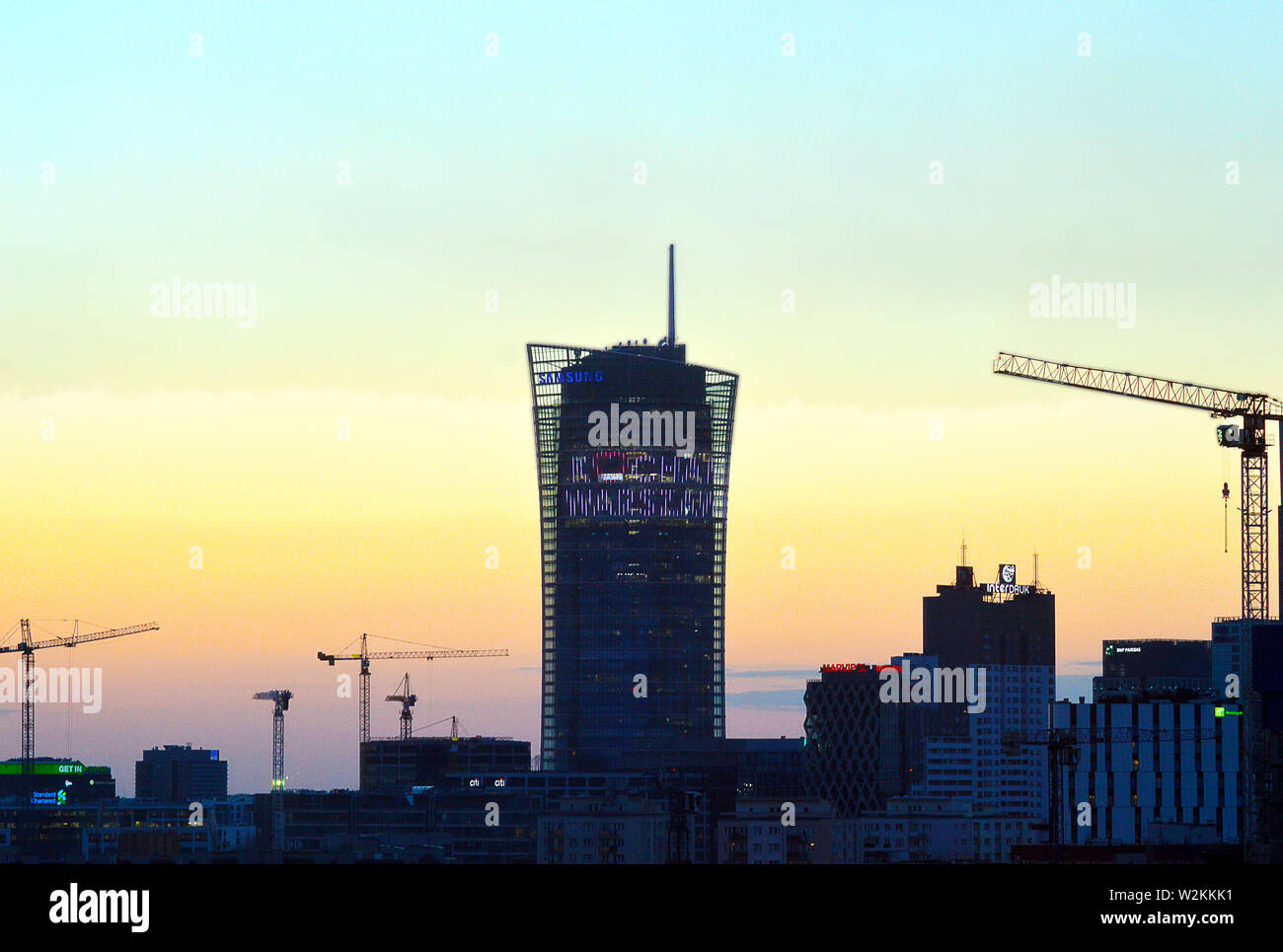 WARSAW, POLAND - 15 APRIL 2019: Dusk falls on the city and the 'kocham warszawe' (I love Warsaw) display lights up on the Samsung Tower Stock Photo