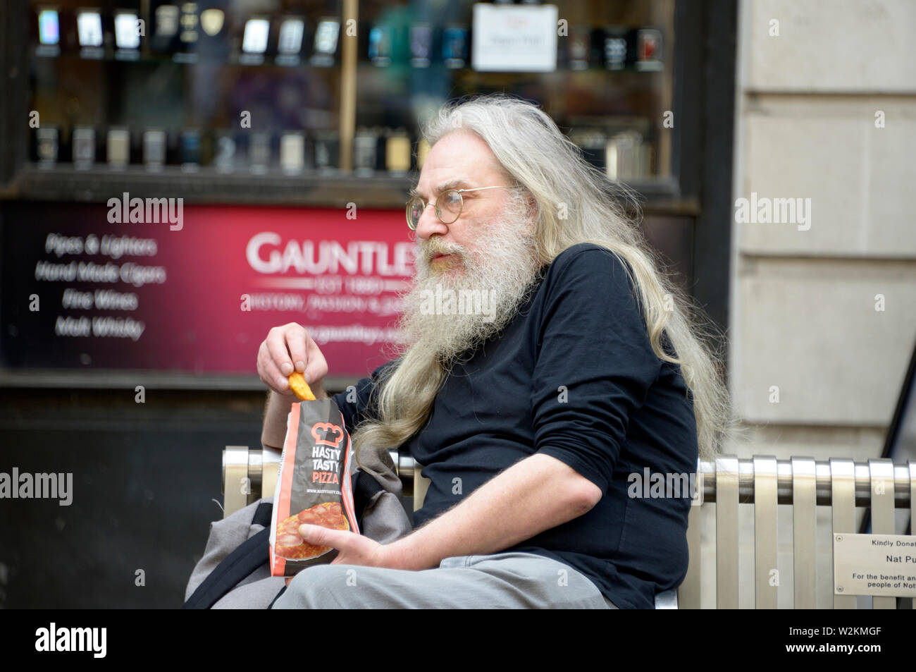 Hairy old man sitting on a bench. Stock Photo