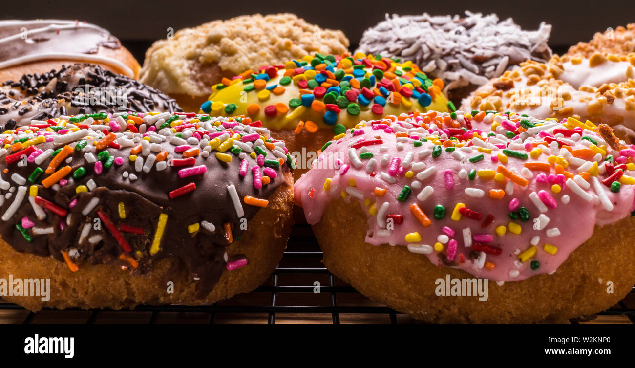 assorted donuts on wire rack on wooden cutting board Stock Photo
