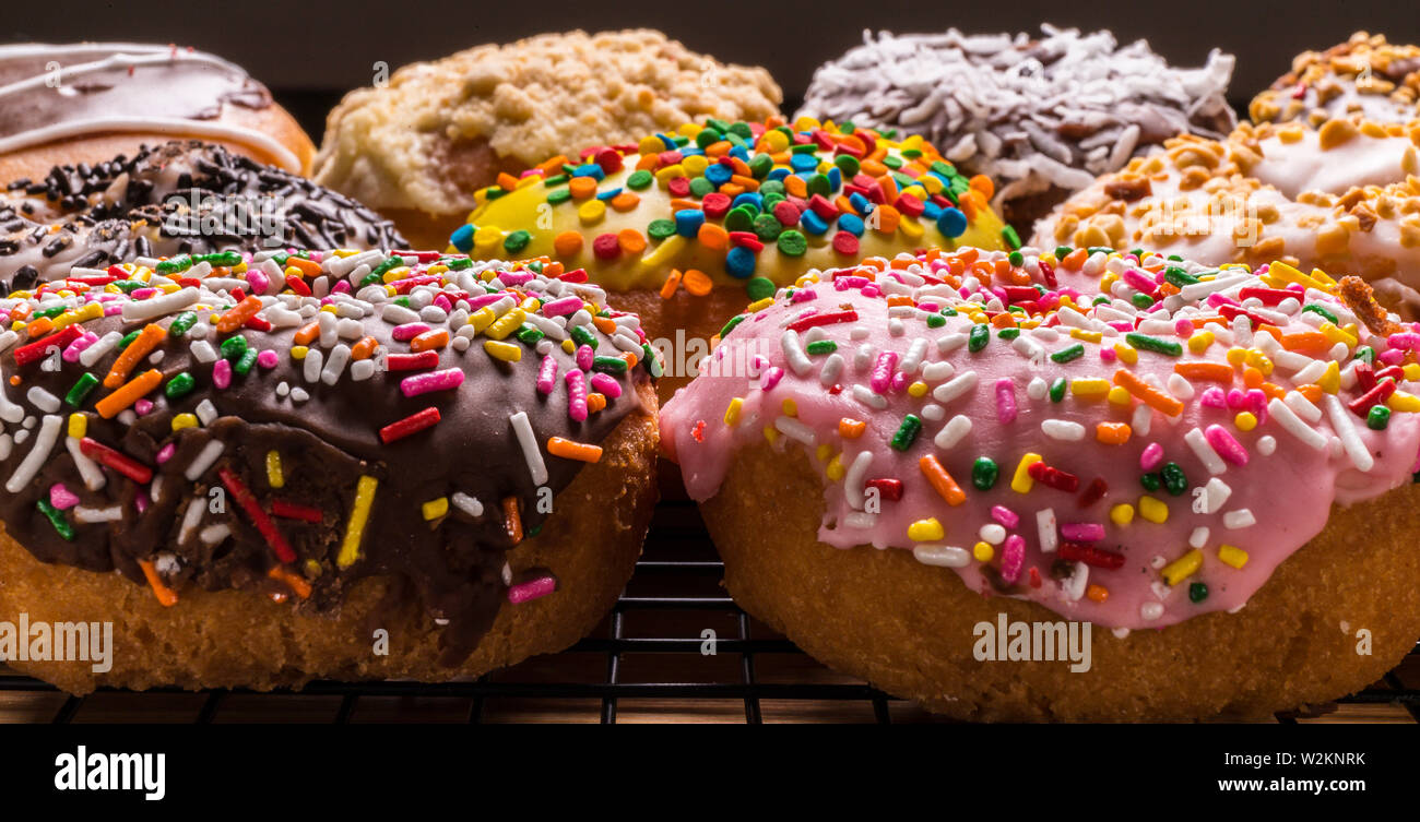 assorted donuts on wire rack on wooden cutting board Stock Photo