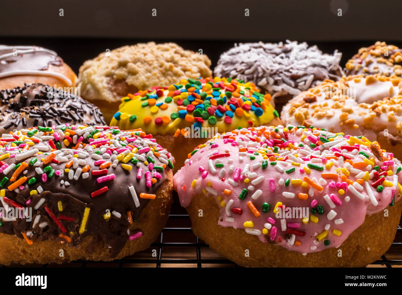 assorted donuts on wire rack on wooden cutting board Stock Photo