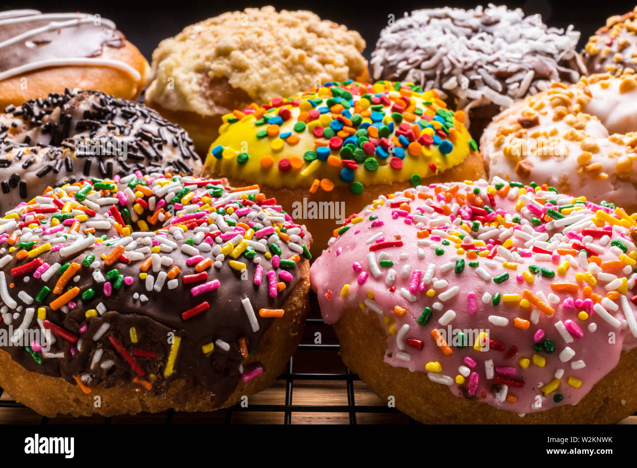 assorted donuts on wire rack on wooden cutting board Stock Photo