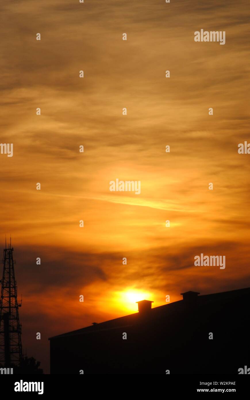 strong orange and yellow natural sunset with silhouette foreground and patterned clouds. Stock Photo