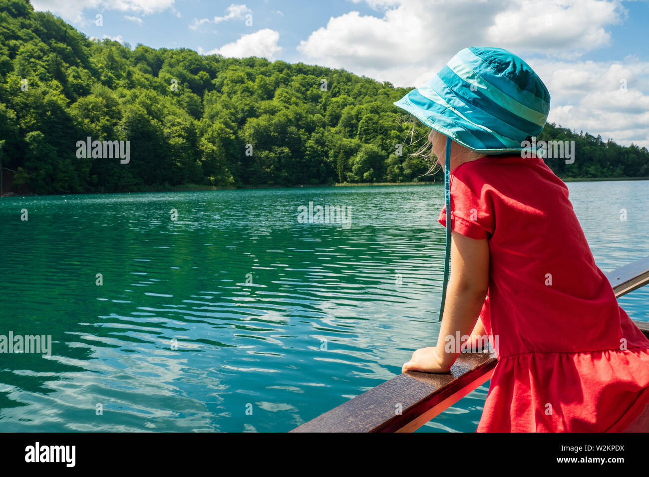 3-year old girl looking over the railing of a ferry cruising on Lake Kozjak at the Plitvice Lakes National Park, Plitvička Jezera, Croatia Stock Photo