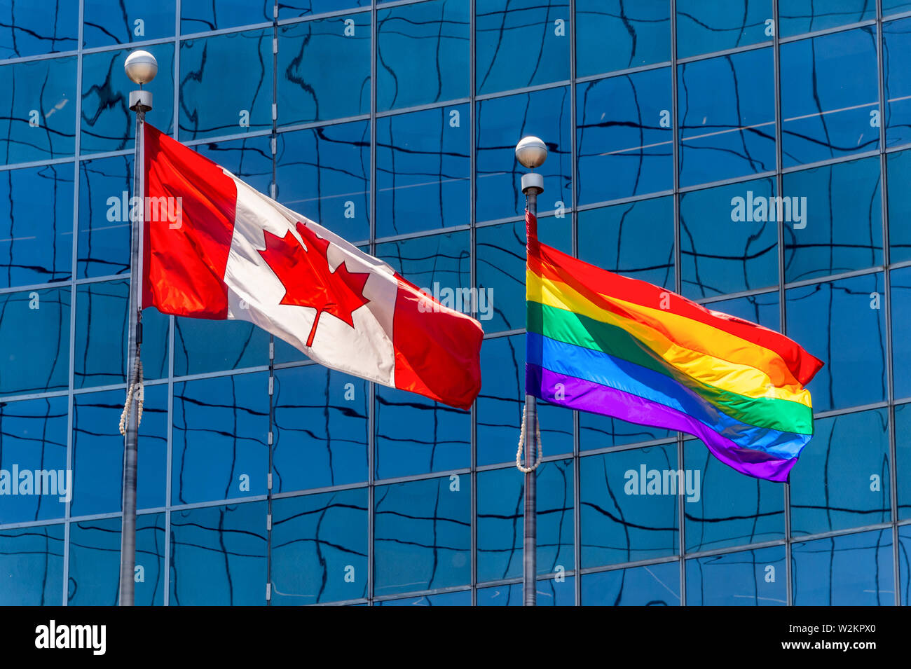 Canadian flag next to rainbow flag in Toronto, Canada Stock Photo