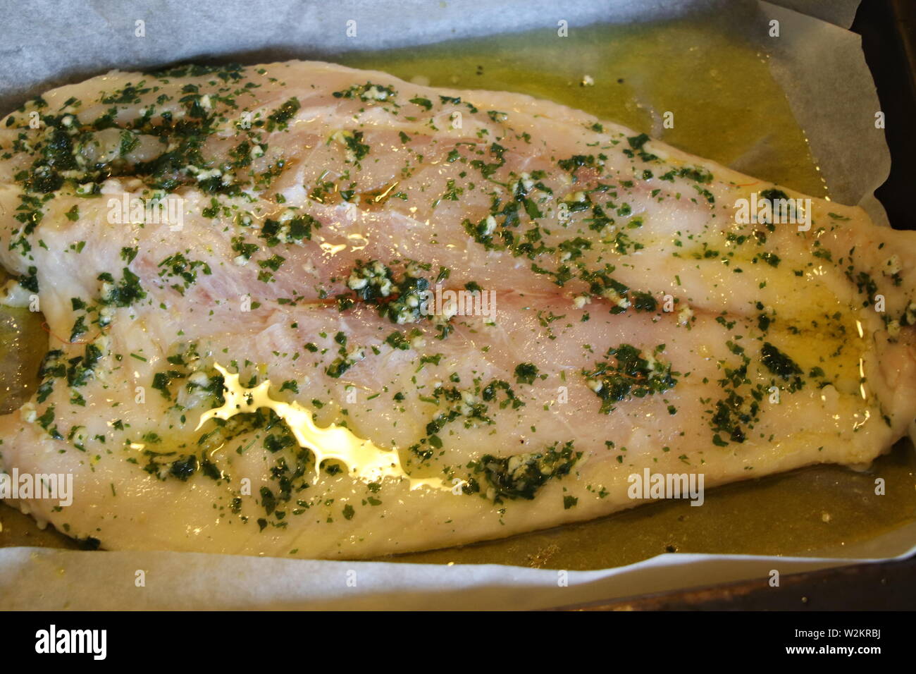 baked white fish fillet with oil and parsley Stock Photo - Alamy