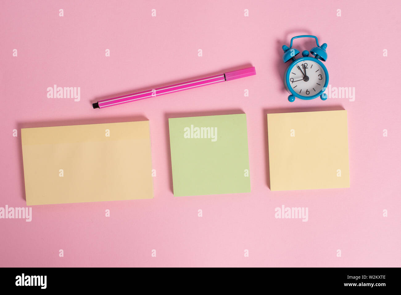 Three multicolor blank notepads alarm clock marker colored background ...