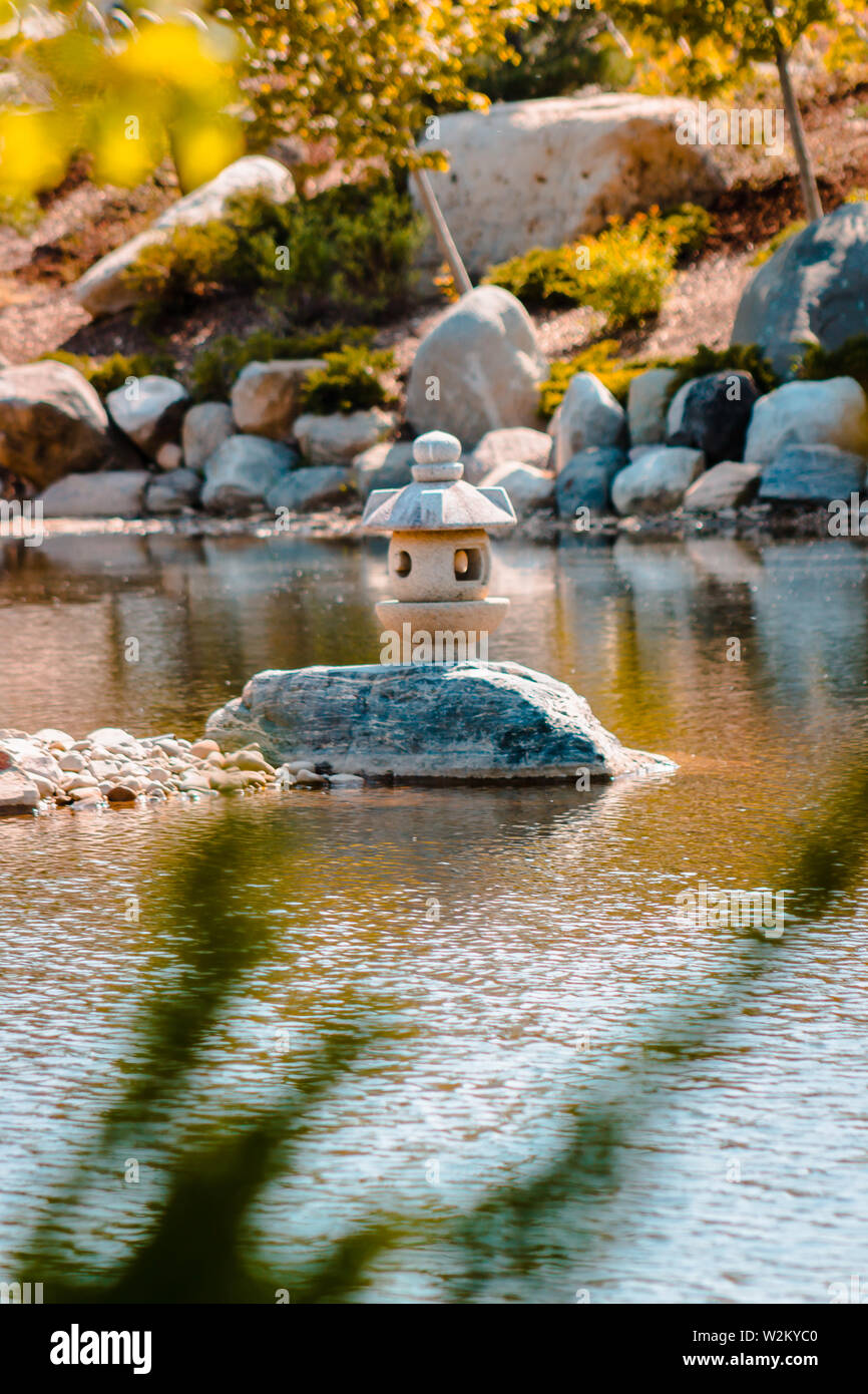 Japanese lantern perched on a rock in the middle of a pond at the Frederik Meijer gardens in Grand Rapids Michigan Stock Photo