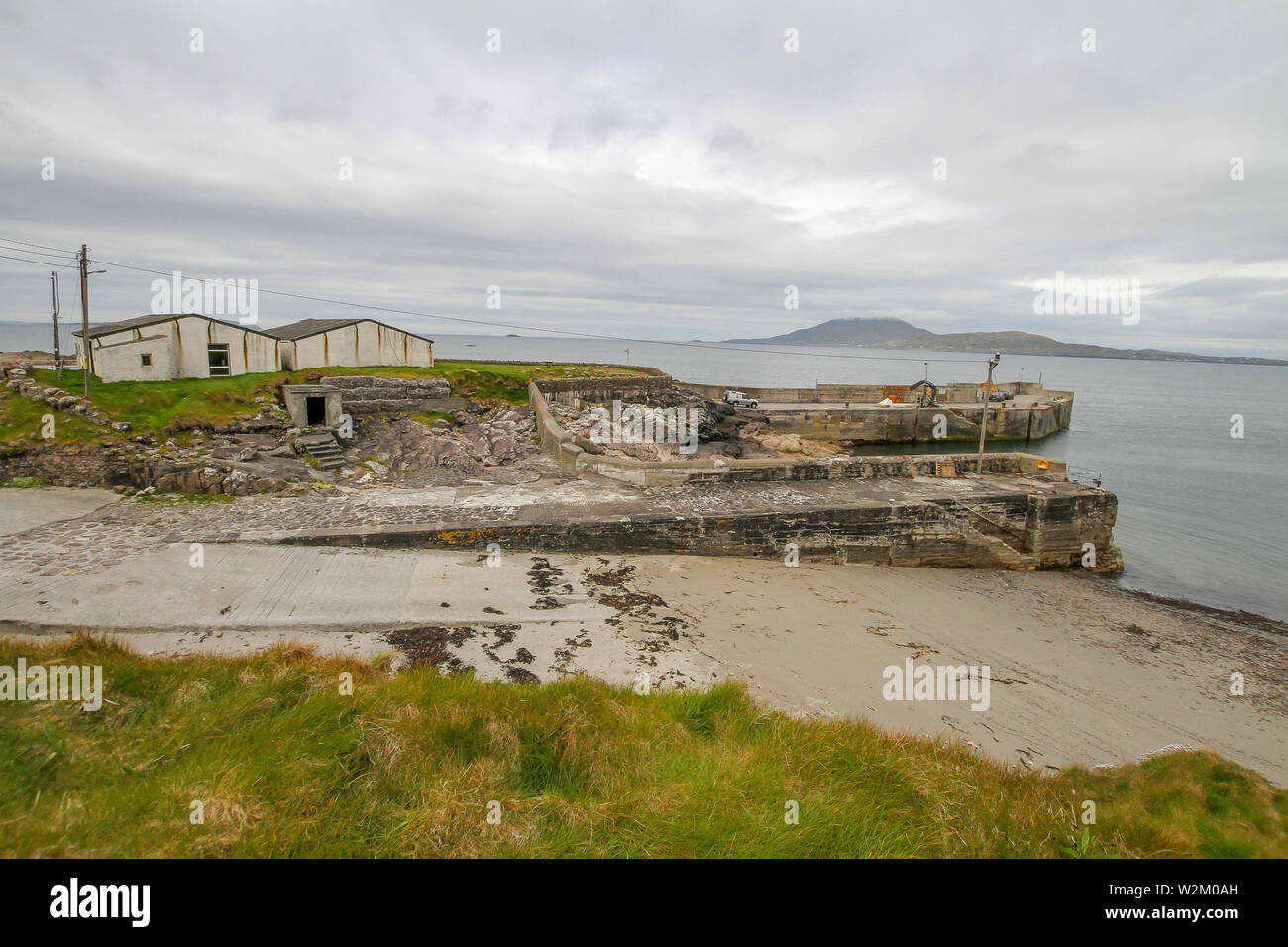Harbour buildings at Roonagh Quay, Louisburgh, County Mayo with Clare Island, across Clew Bay, in the background. Stock Photo