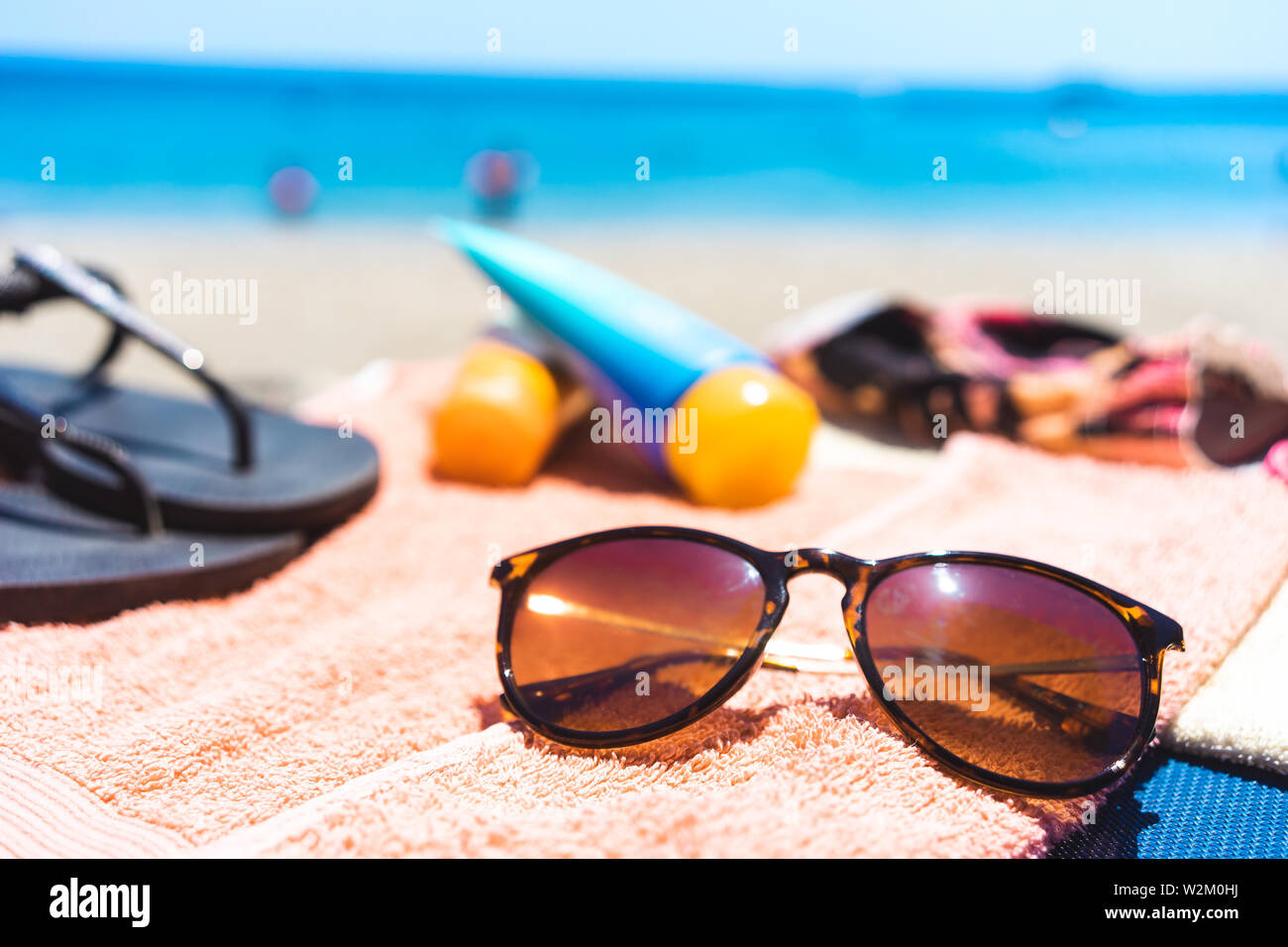 summer vacation: towel with different beach accessories like sunglasses, suncream and flip flops at the ocean Stock Photo