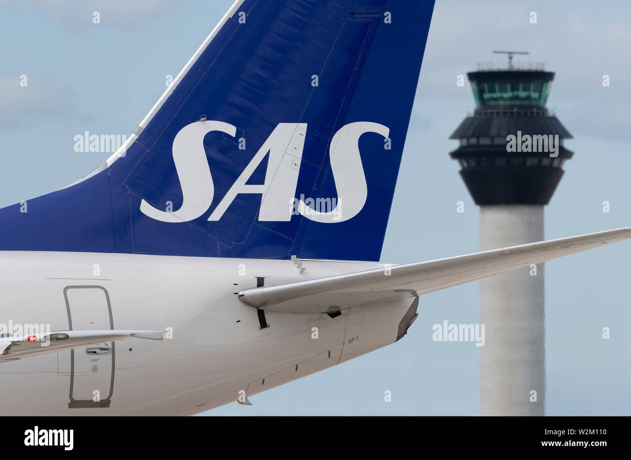 The tailfin of a SAS airliner taxiing along the runway in front of the control tower at Manchester Airport. Stock Photo