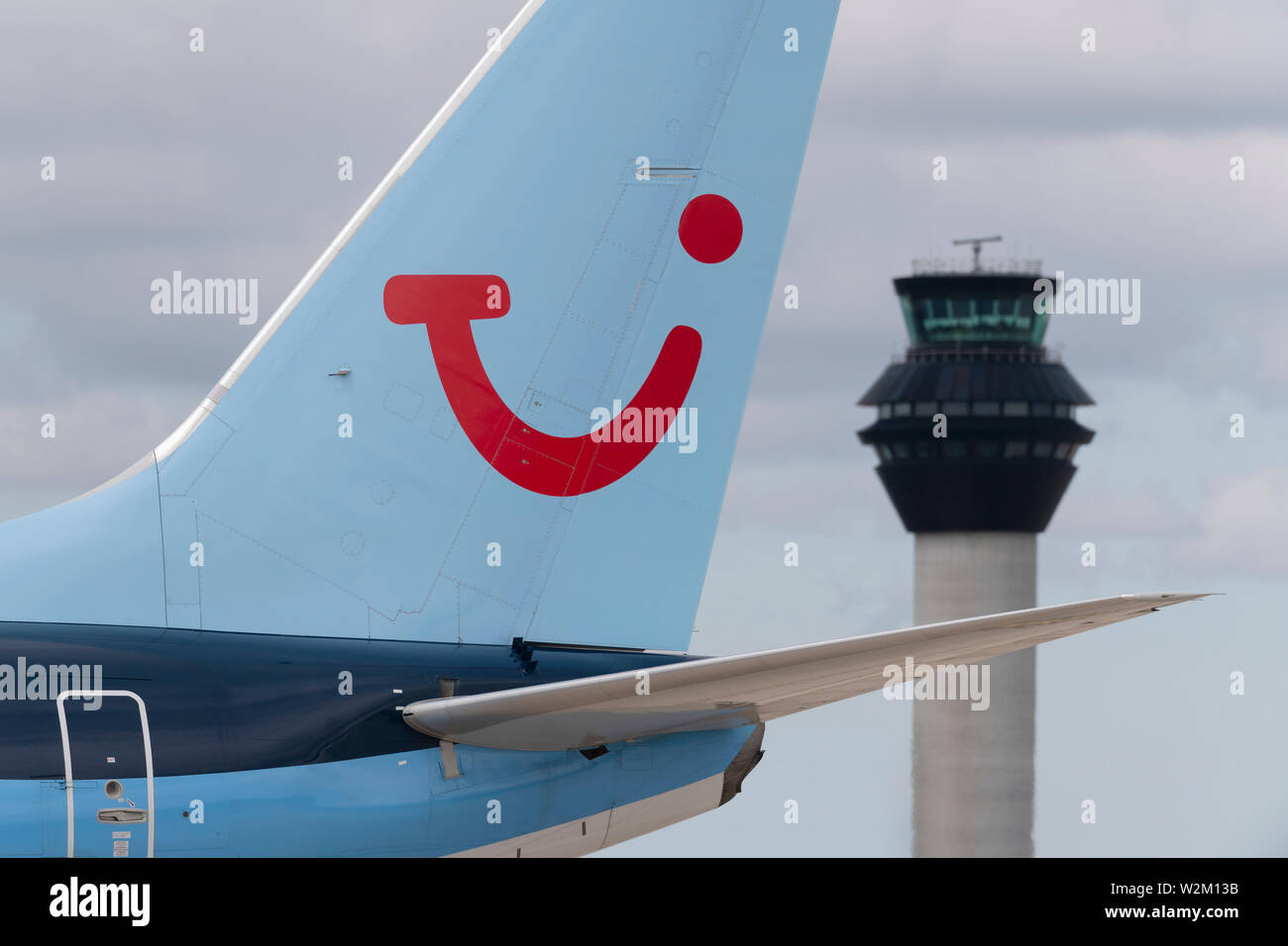 The tailfin of a TUI airliner taxiing along the runway in front of the control tower at Manchester Airport. Stock Photo