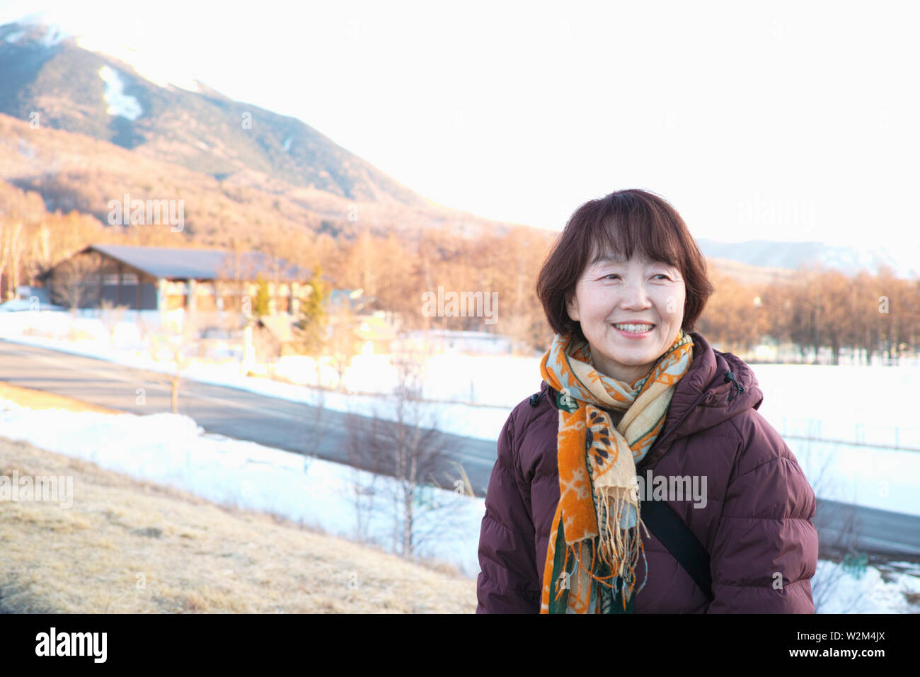An older lady smiling while looking at the Winter scenery Stock Photo