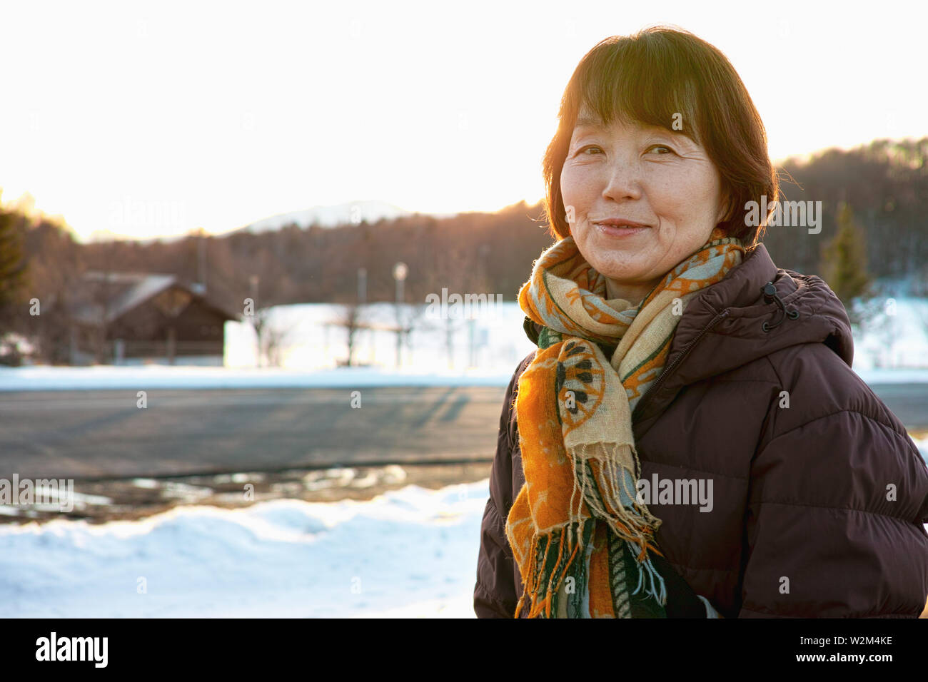 An older lady smiling while looking at the Winter scenery Stock Photo