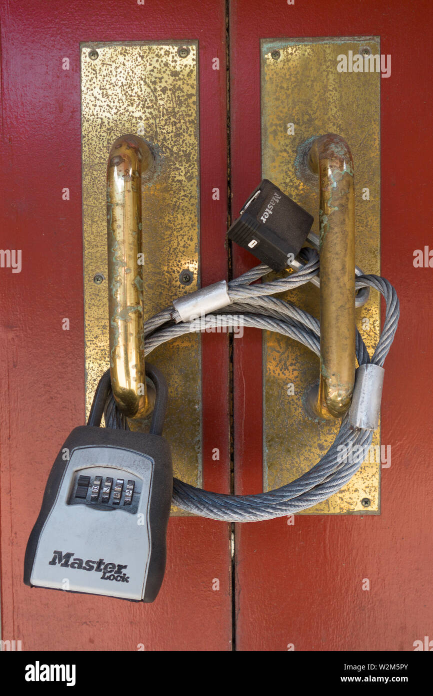 A doorway is secured with heavy metal cable land multiple locks Stock Photo