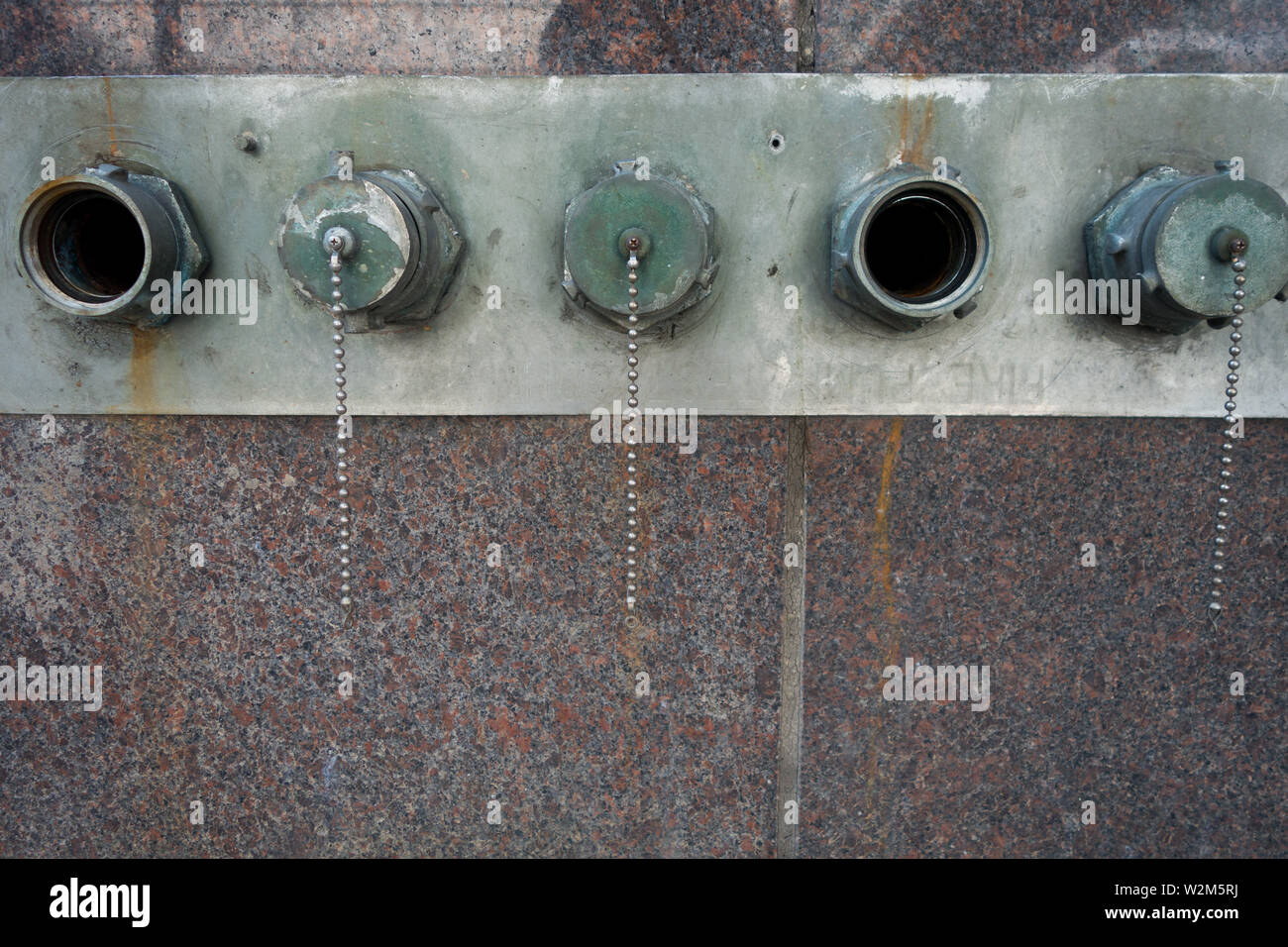 Five standpipe connections aligned on the side of a building, three