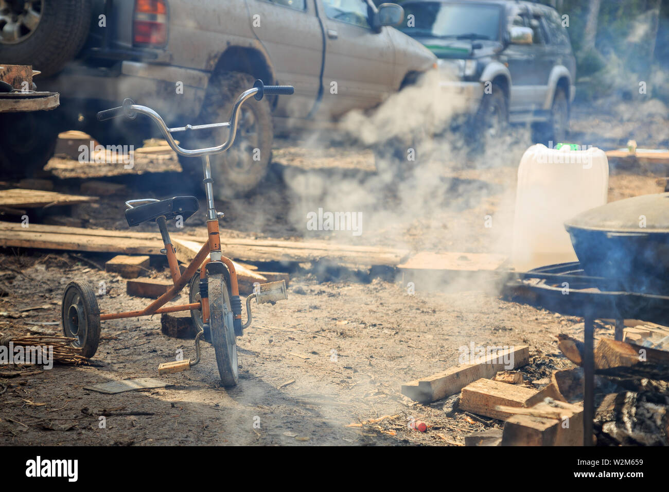 Post apocalypse. Old children's bike in the smoke on the background of cars and chaos. Stock Photo