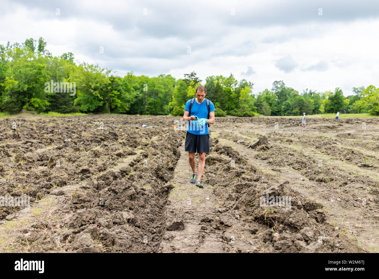 Crater of Diamonds State Park with man walking searching for minerals brown soil in Arkansas dirt landscape meadow field Stock Photo