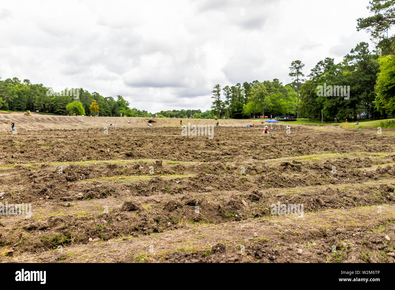 Crater of Diamonds Park with brown soil in Arkansas dirt landscape meadow field and people digging searching for minerals Stock Photo