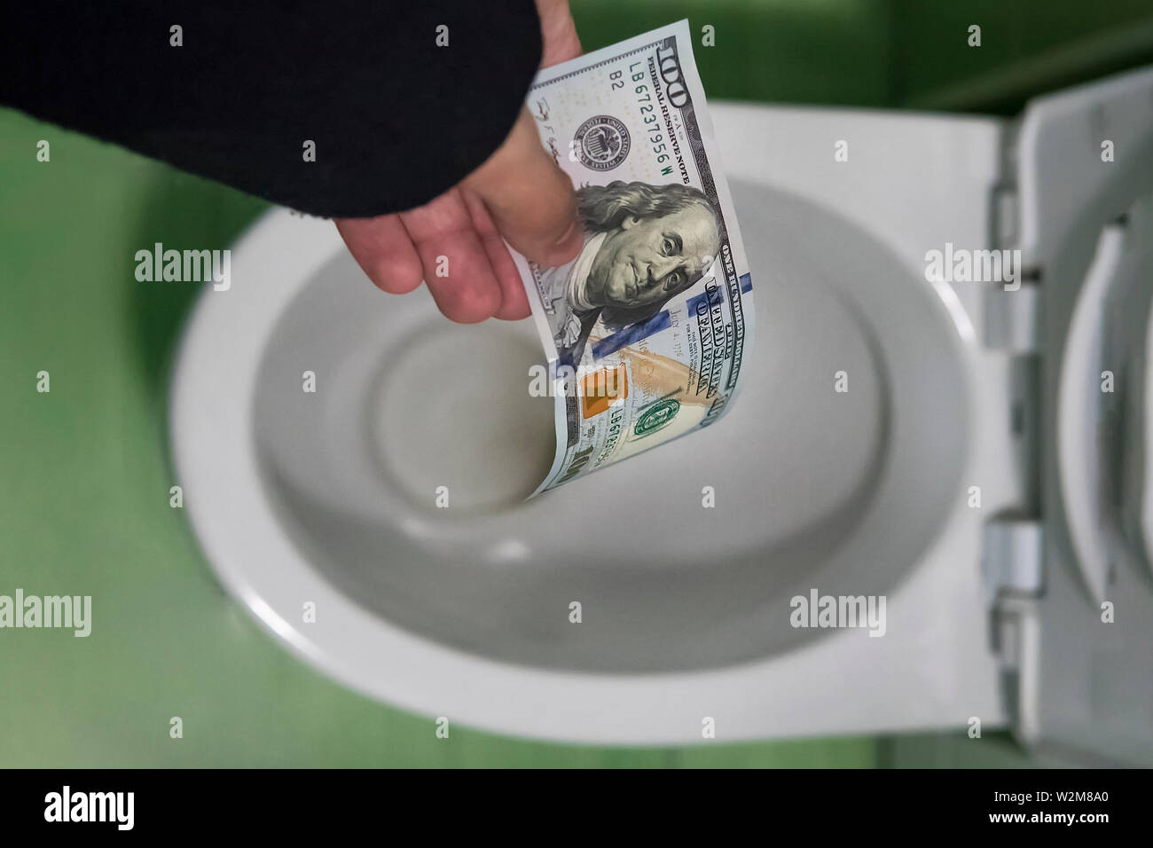 concept of senseless waste of money, loss, useless waste, large water costs, Flushing one hundred dollars down the toilet, loss of money, losing money Stock Photo