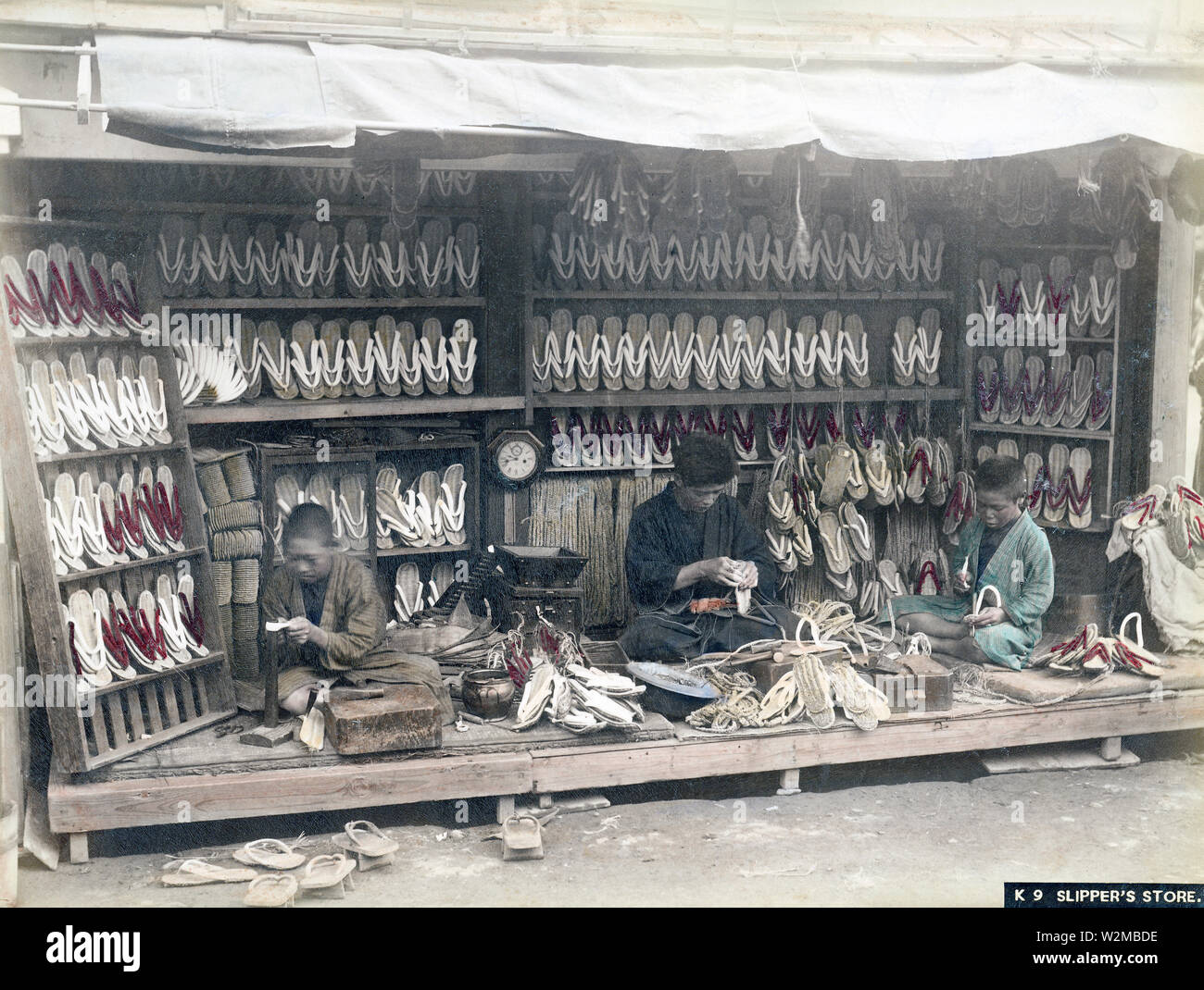 [ 1880s Japan - Geta Clog Shop ] —   A shop selling geta, Japanese wooden shoe wear, ca. 1880s. The roots of geta go back to the Yayoi era, but they became especially popular in the Edo Period (1600–1868). Geta craftsmen offered a wide variety of geta, depending on the fashion of the time.  19th century vintage albumen photograph. Stock Photo