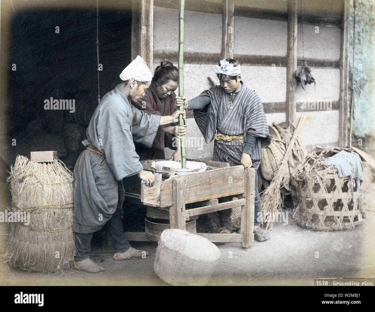 [ 1880s Japan - Japanese Farmers Grinding Rice ] —   Japanese farmers grinding rice to remove the bran, 1880s.  19th century vintage albumen photograph. Stock Photo