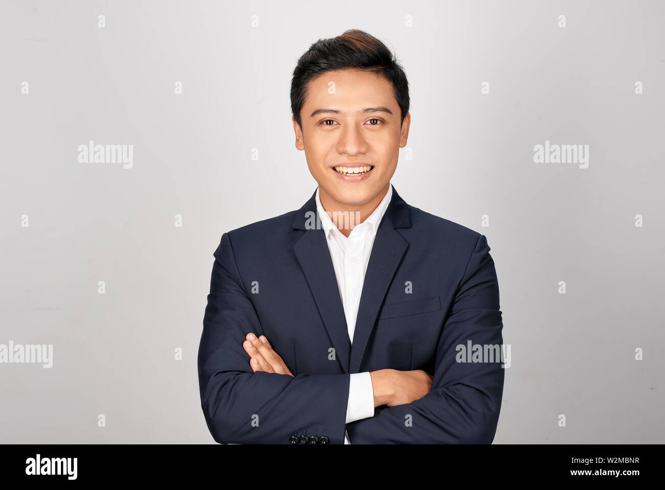 Happy Asian young businessman standing cross-armed on white background Stock Photo