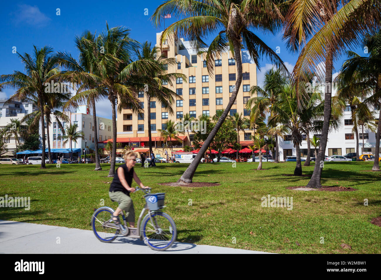 Model released female tourist riding a rental bicycle around Miami's South Beach on a sunny day. Stock Photo