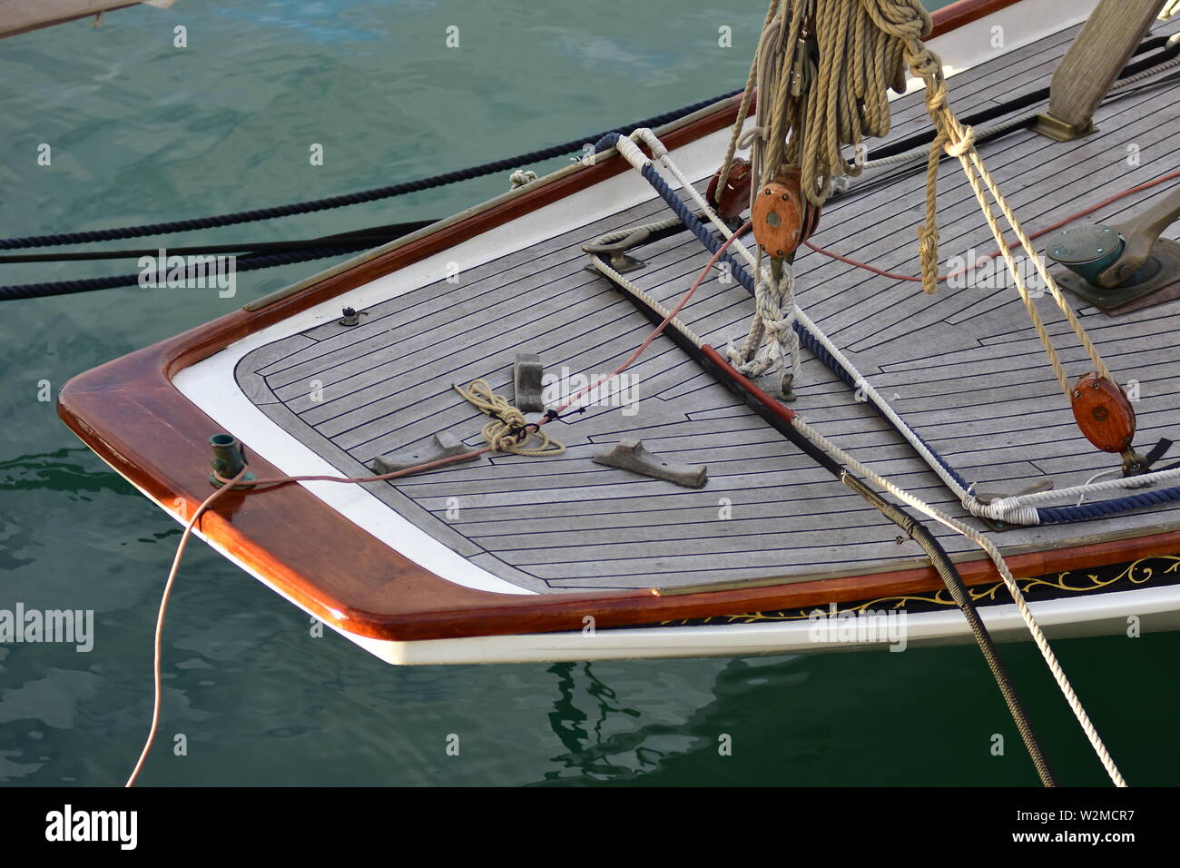 Stern of vintage wooden yacht with teak deck and classic wooden blocks and natural fiber ropes. Stock Photo