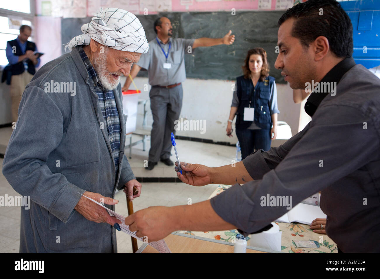 October 23, 2011 – Tunis, Tunisia – An observer woman from the EU Electoral Observation Mission in Tunisia, observes a Tunisian man casting his vote at a polling station during an election in Tunisia. Ten months since the uprising forced the resignation of President Zine el Abidine Ben Ali, 81 political parties, as well as hundreds of independent candidates, competed in the countries first free election. 217 candidates willl serve in the constituent assembly, which will rewrite the country’s constitution and appoint a new government. The election could set the template for other Arab countries Stock Photo