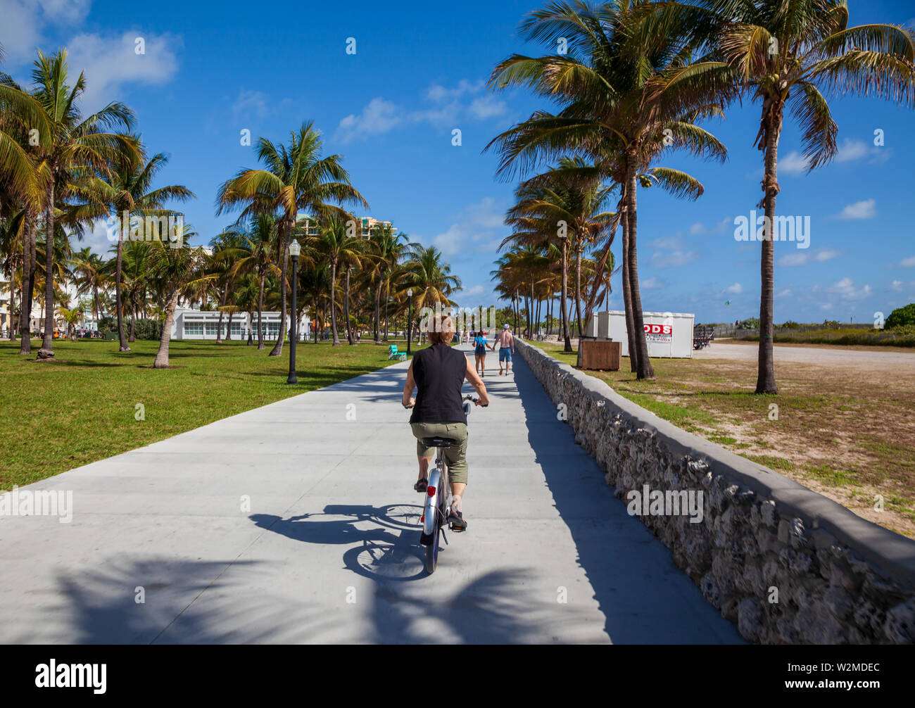 Model released female tourist riding a rental bicycle around Miami's South Beach on a sunny day. Stock Photo