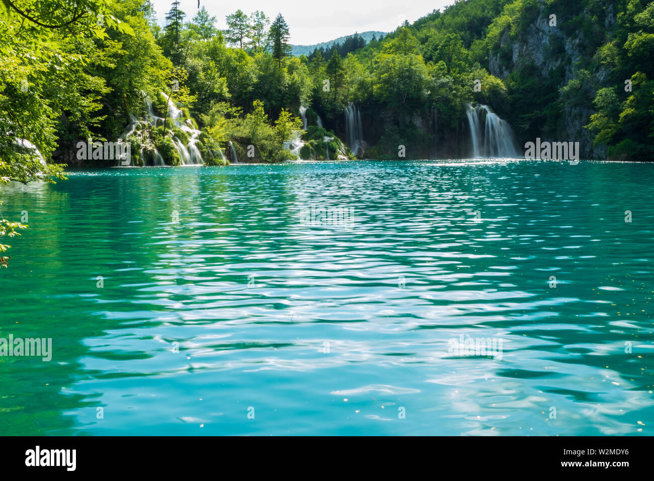 Rushing water cascades down the natural barriers into the crystal clear and azure coloured Lake Milanovac at the Plitvice Lakes National Park, Croatia Stock Photo