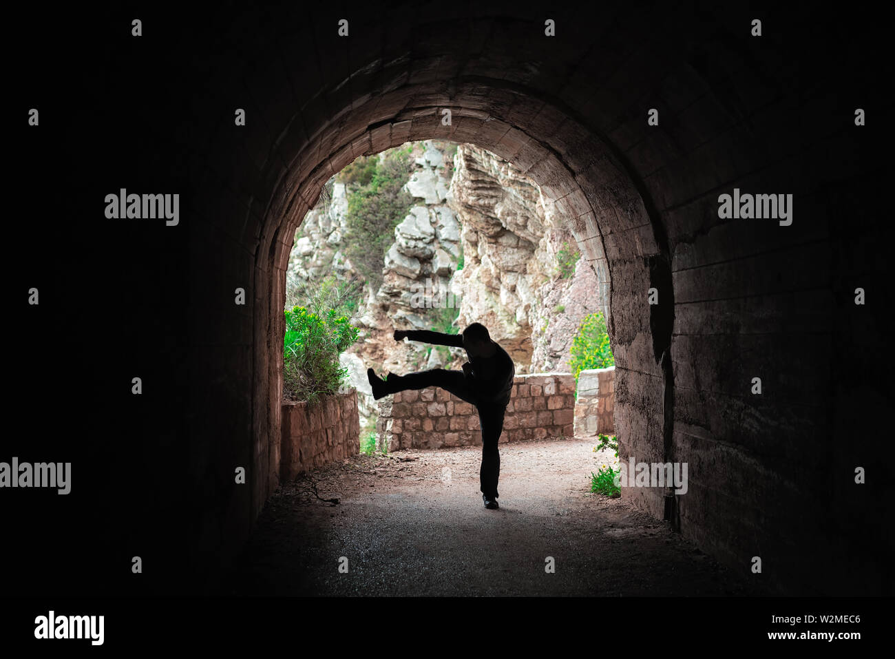 Silhouette of a man practicing karate moves and techniques in a dark tunnel Stock Photo