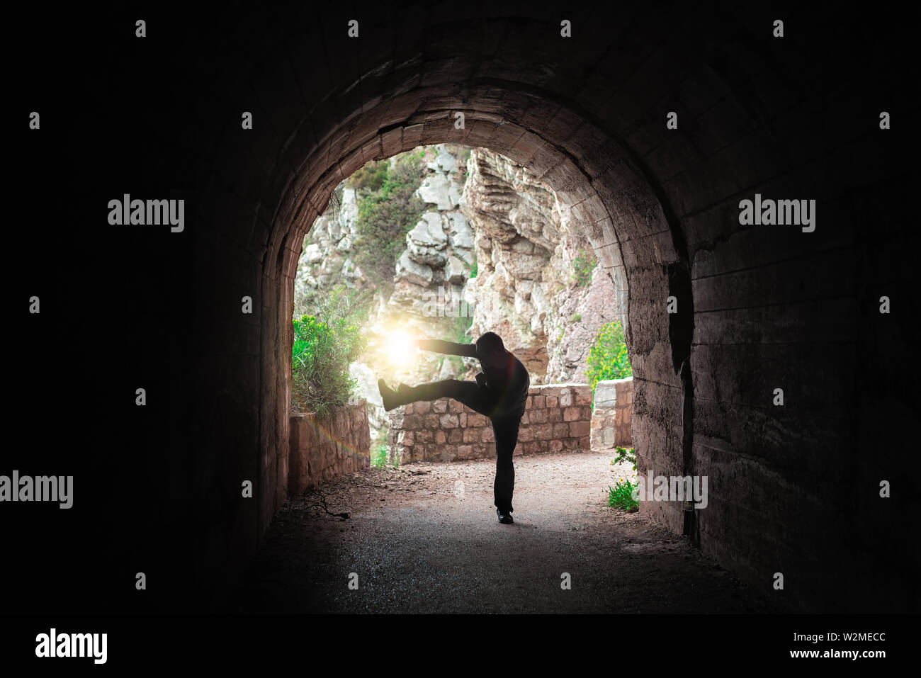 Silhouette of a man practicing karate moves in a dark tunnel Stock Photo