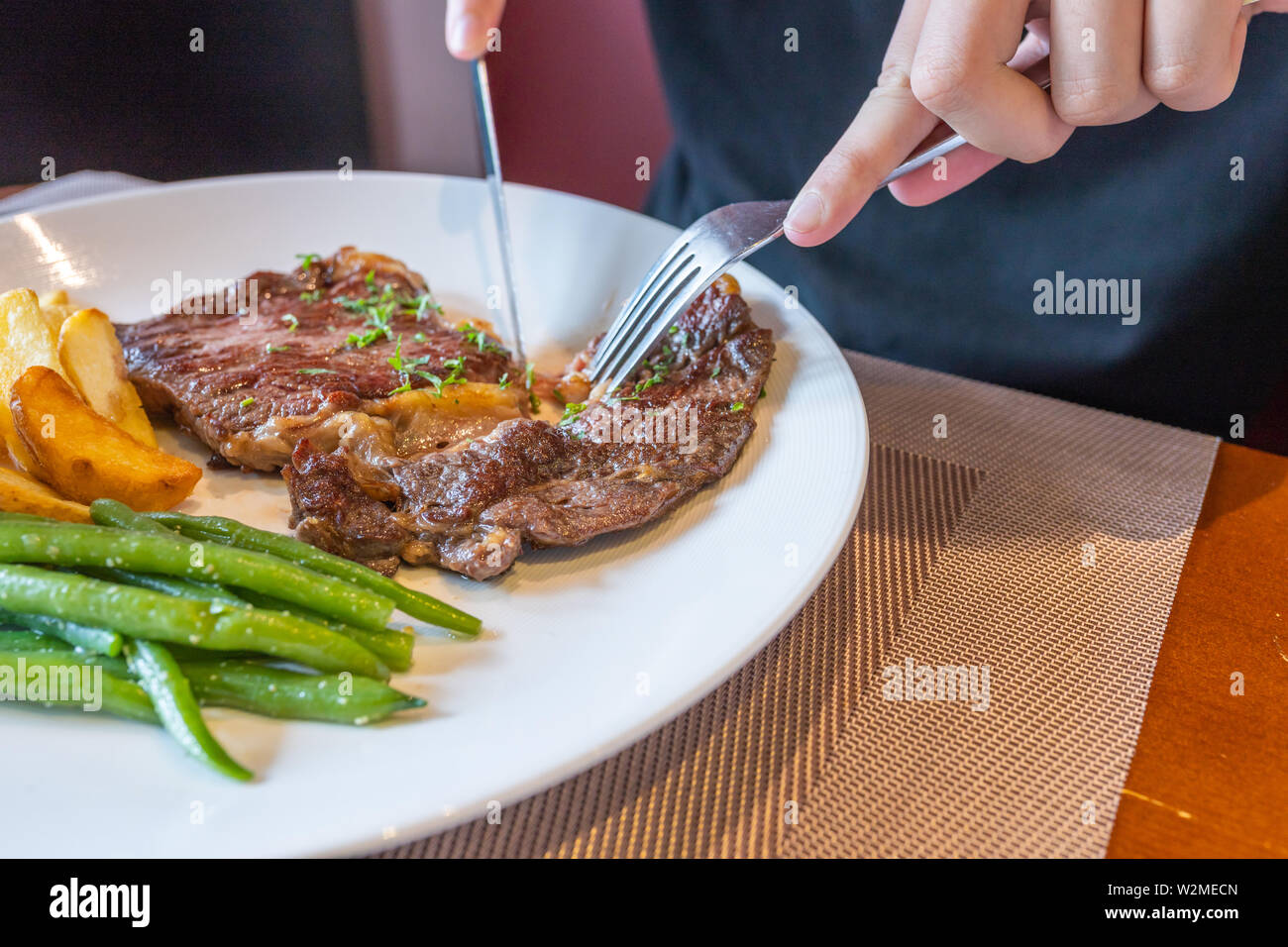Using knife and fork cutting beefsteak on white plate Stock Photo Alamy