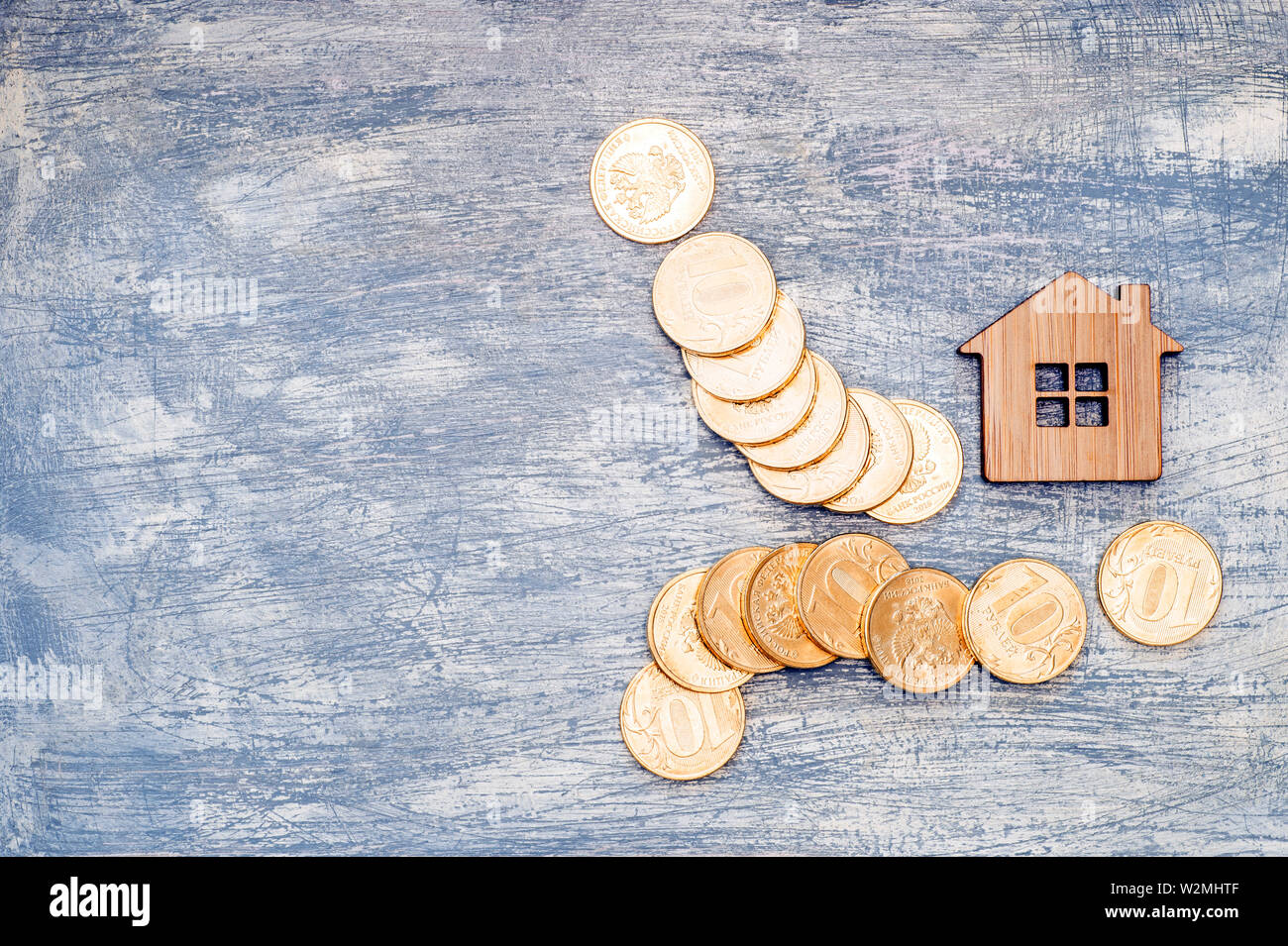 Imitation of a house with metal ten-ruble coins of Russia on a scratched background under the concrete. Stock Photo