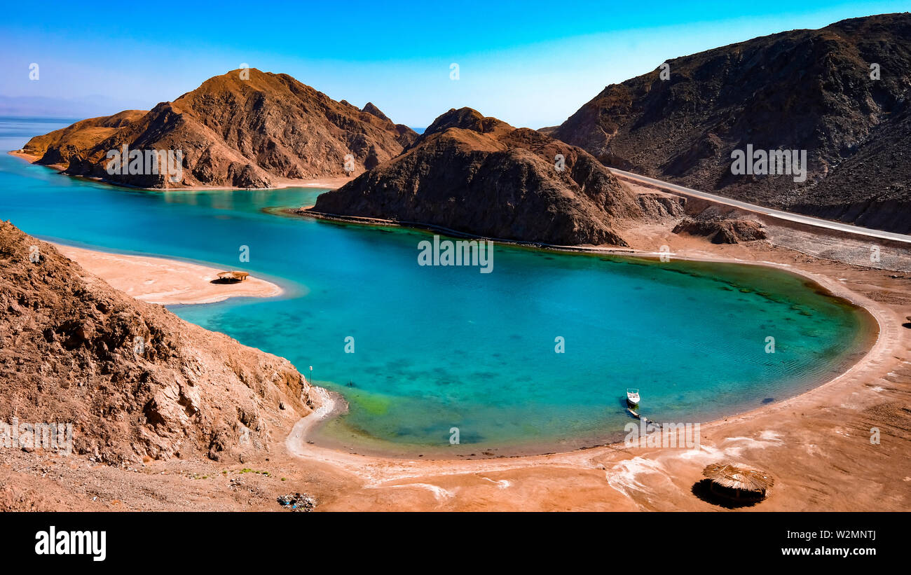 A typical red sea fjord, with clear blue water surrounded by red & yellow mountains, northern Sinai by the red sea, Egypt. Stock Photo