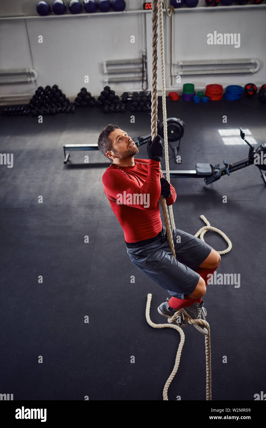 Athlete during rope climb exercise at gym Stock Photo - Alamy