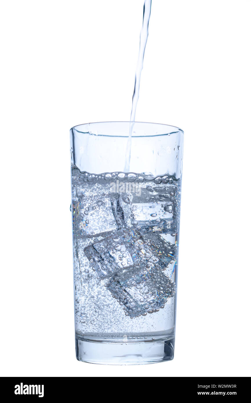 pouring mineral water in transparent glass with ice and bubbles ...
