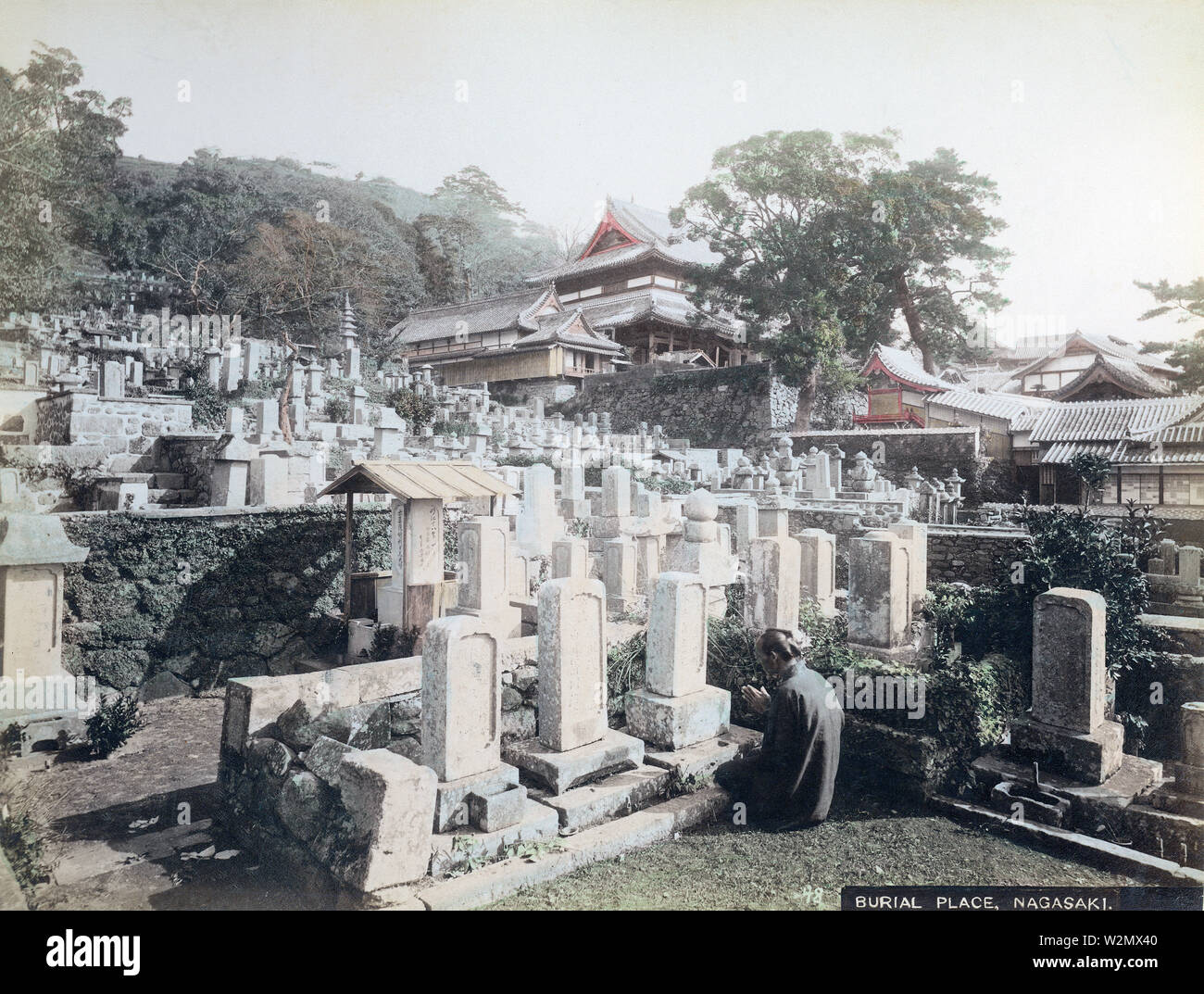 [ 1890s Japan - Praying at Buddhist Cemetary, Nagasaki ] —   A man prays in front of a grave at the cemetery of Honrenji Temple in Chikugo-machi, Nagasaki. Honrenji was destroyed by the atomic bomb in 1945 (Showa 20), but has been gradually rebuilt.  19th century vintage albumen photograph. Stock Photo