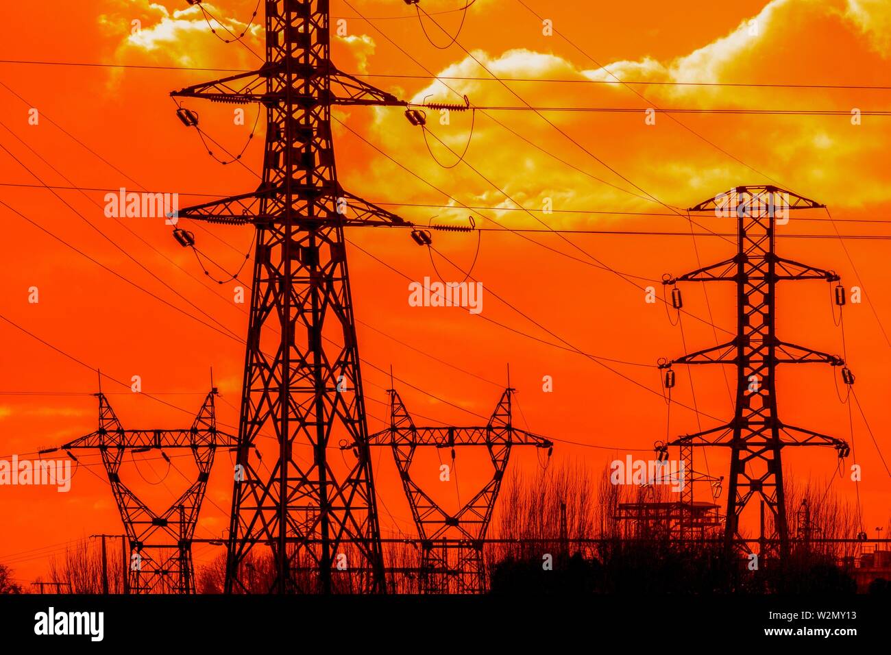 Electricity pylons at sunset, orange sky Stock Photo